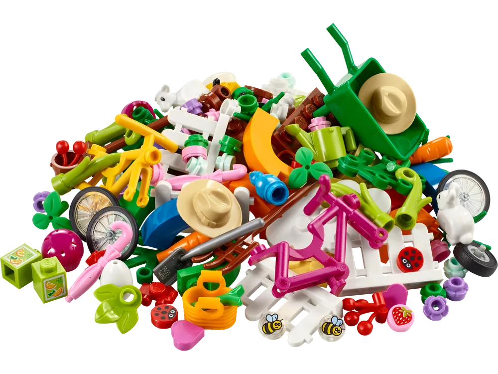 A large pile of diverse LEGO elements from the Spring Fun VIP Add-On Pack, featuring various spring and garden-themed pieces like a wheelbarrow, fences, flowers, bees, ladybugs, carrots, hats, and small animals.