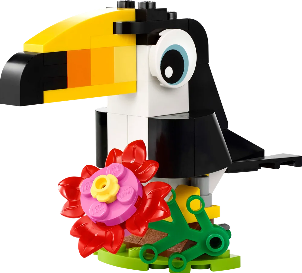 Close-up of the completed LEGO Creator 30688 Tropical Toucan build on a white background, featuring its colorful beak, black and white body, large eye, and a vibrant red and pink flower with green leaf elements at its base.