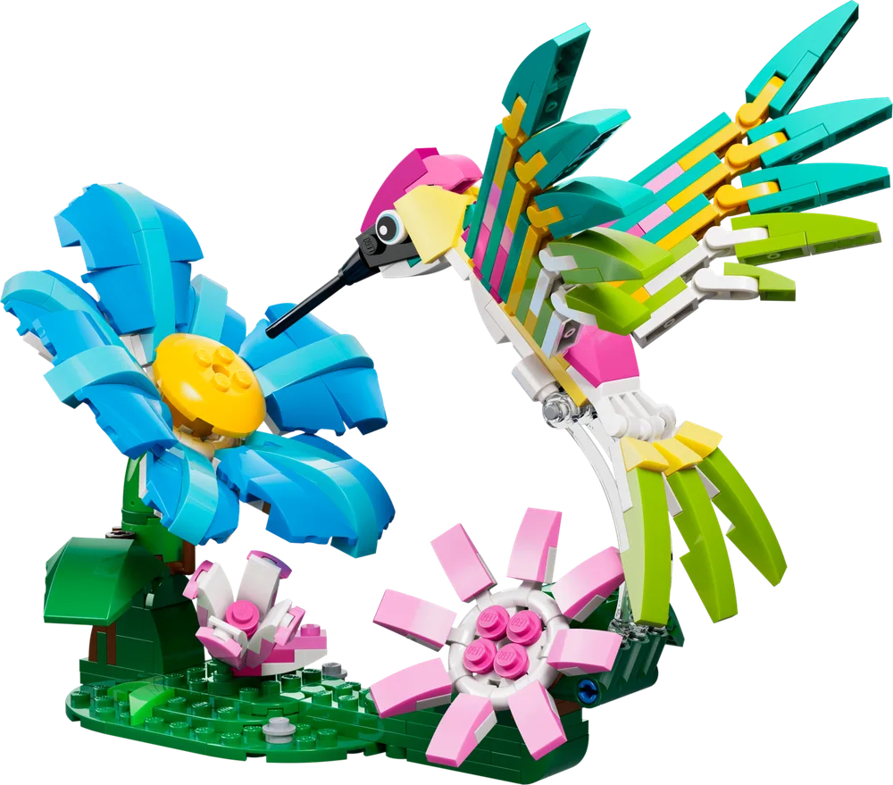 The LEGO Creator 31384 Hummingbird set, showing a colorful hummingbird hovering near a large blue flower and a small pink flower on a green base.