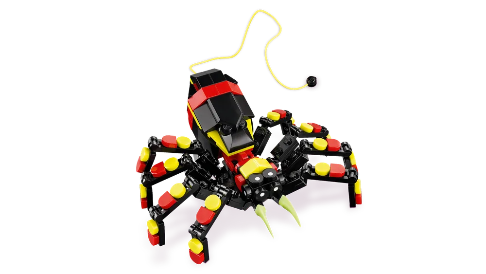 A black, red, and yellow LEGO spider model with eight articulated legs and two light green fangs, shown against a white background with a yellow string extending from its rear.