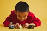 Child arranging LEGO minifigures and cars.