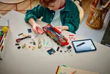 Child building LEGO fire truck with digital instructions.