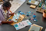 Person building LEGO ice slide with instructions.