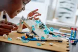 Person interacting with LEGO penguin ice slide.