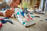 Child playing with sled on LEGO ramp.