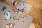 Overhead view of girl building LEGO castle with digital instructions.