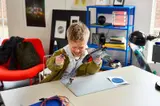 Boy laughing and playing with LEGO Quinjet and Captain America.