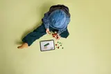 Child building LEGO Aquilops with tablet.
