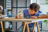 Child admiring BB-8 on desk.