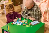Girl and adult building LEGO set.