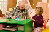 Girl and adult playing with LEGO set.