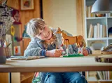 Child smiling at LEGO horse model.