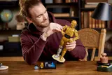 Man adjusting C-3PO build's arm.