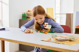 Girl playing with LEGO Minecraft Chicken Farm set.