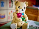 LEGO teddy bear holding a pink rose.