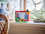 LEGO Christmas frame on a windowsill with a snowy forest photo.