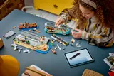 Child building LEGO streetcar set with digital instructions.