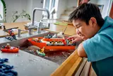 Child playing with floating LEGO boat.