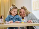 Child and adult building LEGO set.