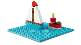 LEGO sailboat and lighthouse on a blue baseplate.