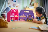 Child interacting with open dollhouse cases.