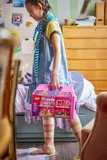Child carrying the closed dollhouse suitcase.