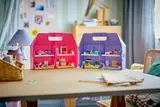 Open pink and purple dollhouse cases on a table.