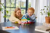 Adult and child building a large LEGO house.