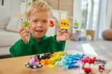 Boy smiling, holding LEGO alien and planet.