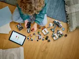 Child building with LEGO set and tablet.