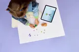 Child building LEGO with digital instructions.