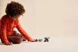 Child playing with minifigures and transport.