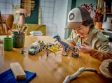 Child playing with LEGO Allosaurus Transport Truck set.