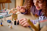 Close-up of hands posing LEGO Dobby on a table.