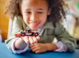 Child holding a LEGO F1 race car.