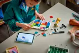 Person building LEGO FIFA 2026 emblem with tablet.