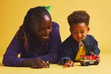 Adult and child playing with fire truck set.