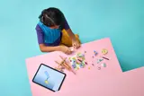 Child building LEGO Floral Art with tablet.