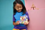 Child holding finished LEGO butterfly art.