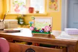 Floral LEGO frame on a wooden desk.