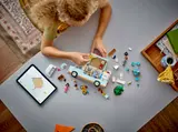 Child building LEGO Friends Camper Van with tablet.