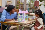Adult and child playing with dollhouse.