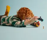 Child playing with LEGO go-kart and minifigure.