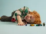 Child smiling with LEGO go-karts and minifigures.