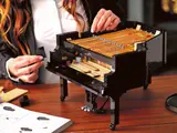 Hands building LEGO Grand Piano side panel.