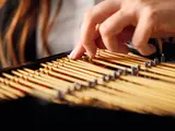 Hand adjusting LEGO piano strings.
