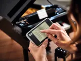 Hands scrolling LEGO piano app song list.