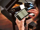 Hands with phone showing digital sheet music.