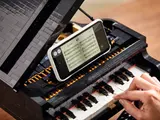 Playing LEGO piano with app displaying sheet music.