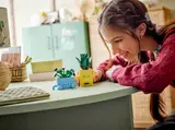 Person admiring LEGO Happy Plants on a desk.